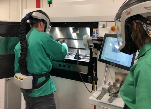 Two additive technicians setting up the 3-D Printing Machine to make a prototype.