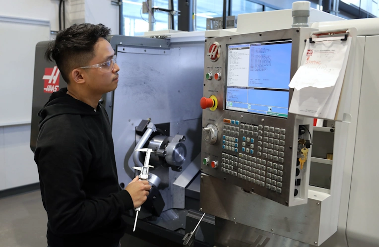 CNC Lathe machinist doing First Article Inspection of a piece coming off the machine.