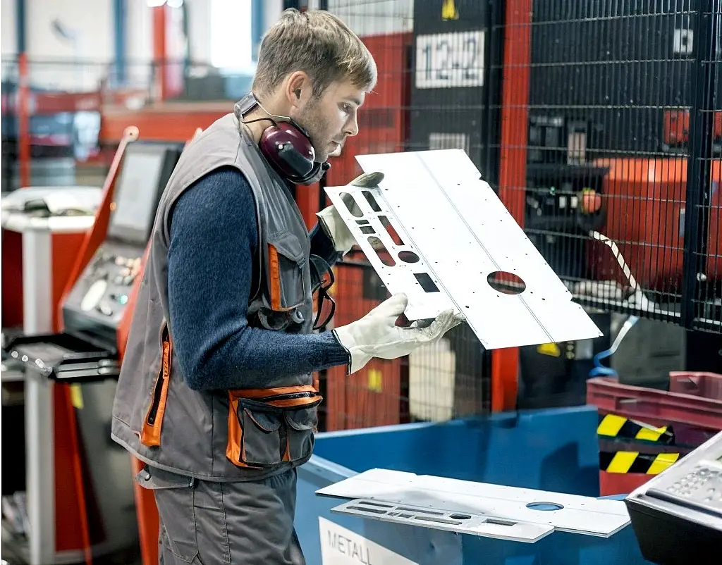 Metal Fabrication Specialist inspecting sheet metal parts.