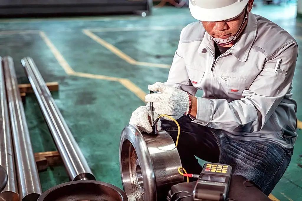 An NDT Inspector using UT (Ultrasonic Testing) to inspect a part.