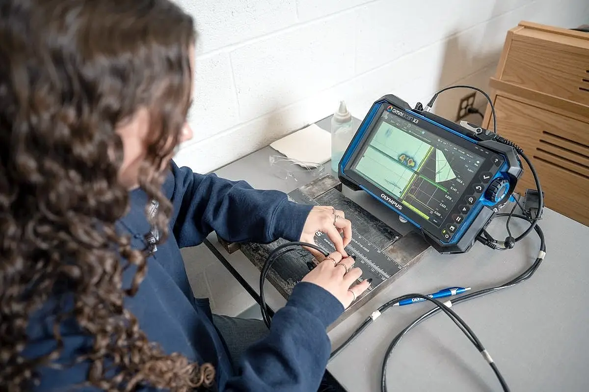 An NDT Inspector analyzing a metal part off of a CNC Millling machine.