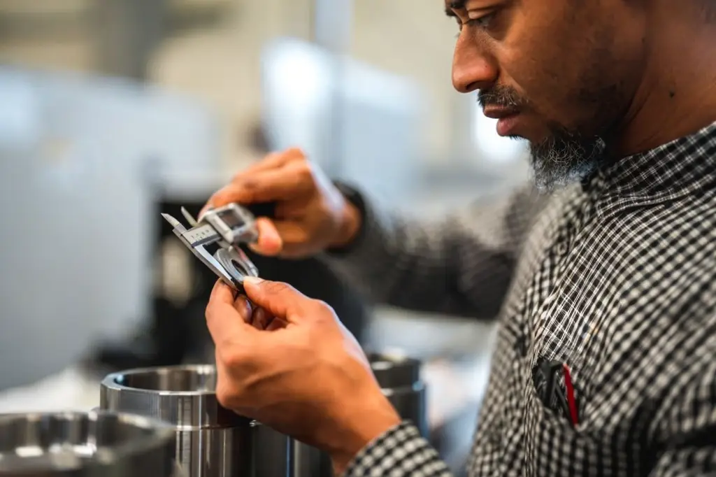 A QC Inspector inspects a CNC Machined part coming off the machine.