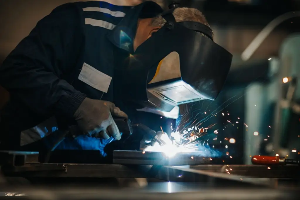 Welder using MIG process to fuse two steel parts together.